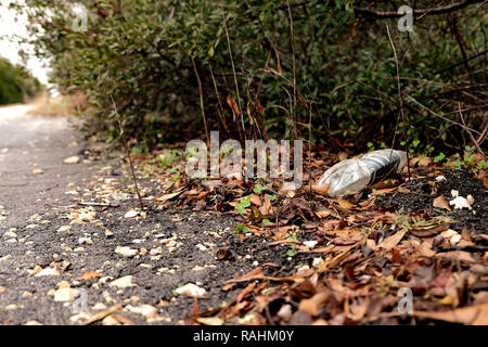 Crushed plastic bottle by the side of the road; plastic pollution; trash on the side of the road. Stock Photo