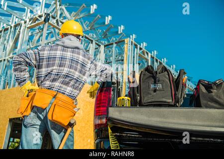Construction Contractor Job. Caucasian Worker Wearing Yellow Safety Hard Hat in Front of Newly Developed Building. Stock Photo