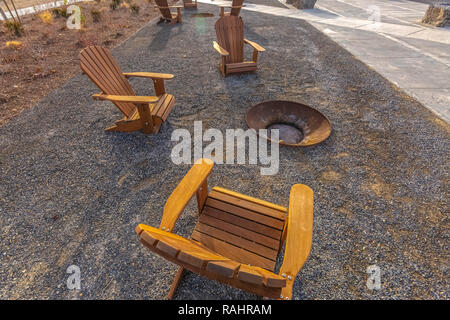 Wooden chairs sitting around a fire pit in park Stock Photo
