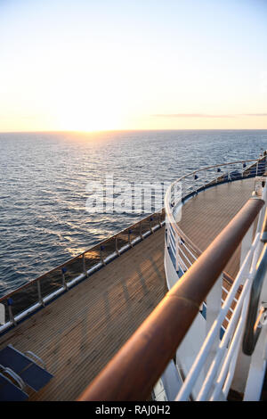 Railing and deck flooring of a cruise ship at sunset with the ocean in ...