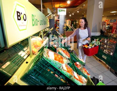 Woman shopping for organic produce in the fruit and vegetable section of a self-service grocery department, supermarket Stock Photo