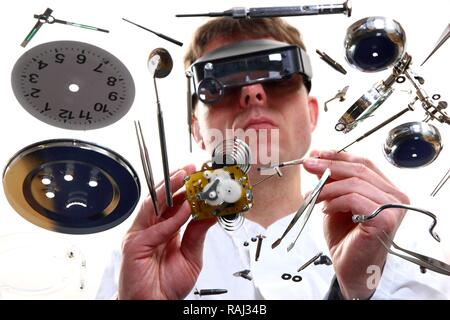 Precision mechanics, watchmaker repairing a clockwork, alarm clock, using a head-worn loupe system Stock Photo