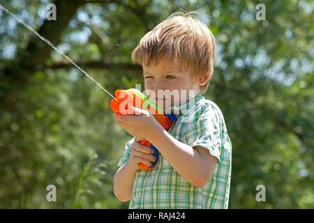 Little boy playing with a water pistol Stock Photo