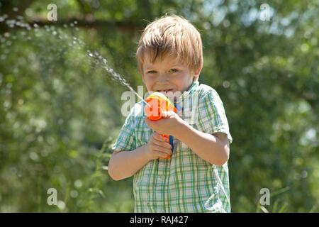 Little boy playing with a water pistol Stock Photo