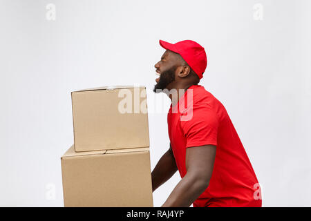 Portrait of delivery african american man in red shirt. he lifting heavy weight boxes against having a isolated on the white background. Stock Photo