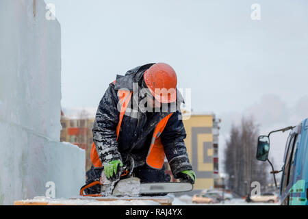 Worker in orange vest and hard hat is checking the chainsaw chain Stock Photo