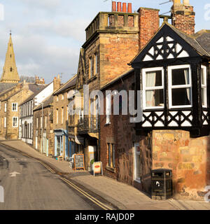 Bin stands in front of a half-timbered facade at Alnmouth in Northumberland, England. The litter bin stands on the pavement. Stock Photo