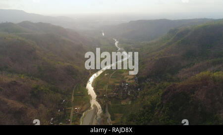 aerial view river canyon among farm lands rice terraces. river in mountain canyon, gorge, among hills covered with vegetation, trees at sunset. tropical landscape