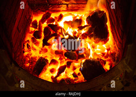 An open fire burning in wintertime. Ebmers glow bright within the hearth. Stock Photo