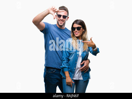 Young couple in love wearing sunglasses over isolated background smiling making frame with hands and fingers with happy face. Creativity and photograp Stock Photo