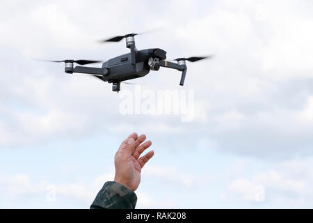 Hand catching drone aircraft in sky background, camera operator concept Stock Photo