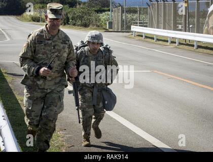 Torii Station, Okinawa (Feb 12, 2017) –Sgt. Maj. Juan Rosario-Montalvo (left) and Sgt.Keila Hernandez  run together to the finish line of the 12-mile ruck march during the US Army Japans best warrior competition. The top competitors of this competition will continue on to compete in a pacific-wide competition in Hawaii. Stock Photo