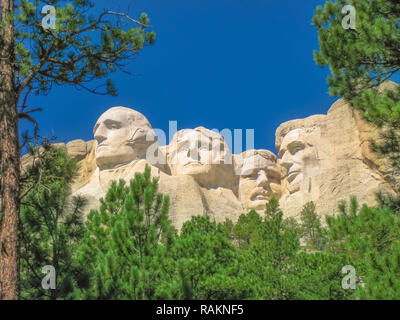 Mount Rushmore National Memorial is a sculptural rock complex in South Dakota, Black Hills, made up of huge granite blocks. The presidents are: Washington, Jefferson, Roosevelt, and Lincoln. Blue sky. Stock Photo