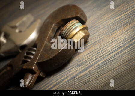 Close up vintage rusty adjustable wrench on a weathered wood background. Plumbing DIY repair concept Stock Photo
