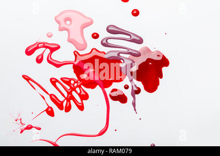 top view of abstract spilled red and pink drops of nail polish isolated on grey Stock Photo