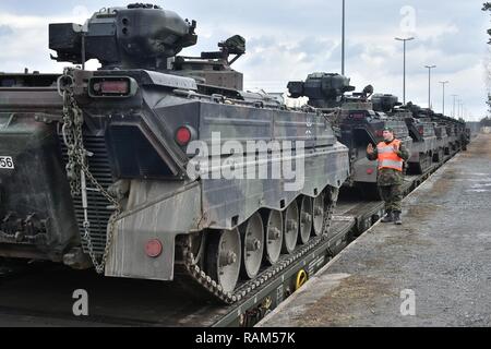 German soldiers with the 122nd Mechanized Infantry Battalion, 12th Armored Brigade, 10. Panzer Division, load tracked Marder infantry fighting vehicles onto railroad carts at the 7th Army Training Command’s Grafenwoehr Tower Barracks railhead station, Germany, Feb. 21, 2017. The unit deploys to the Baltics as part of NATO's Enhanced Forward Presence. Stock Photo