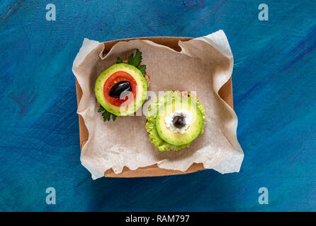 Two vegetarian sandwiches in small packing box on blue background. Stock Photo