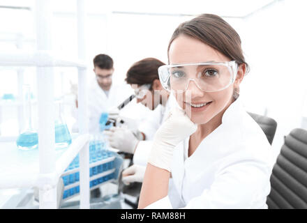Investigator checking test tubes, Woman wears protective goggles Stock Photo