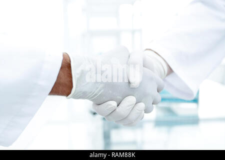 Handshake with white medical gloves Stock Photo