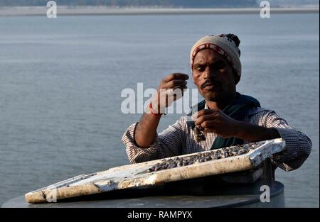 A fisherman bait a fish hook on the banks of Brahmaputra river to fish in Guwahati, Assam, India on Friday, January 4, 2019. PHOTO: DAVID TALUKDAR. Stock Photo