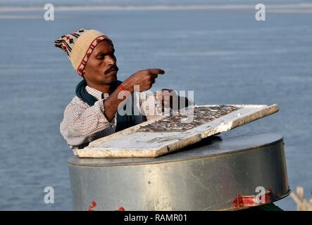 A fisherman bait a fish hook on the banks of Brahmaputra river to fish in Guwahati, Assam, India on Friday, January 4, 2019. PHOTO: DAVID TALUKDAR. Stock Photo