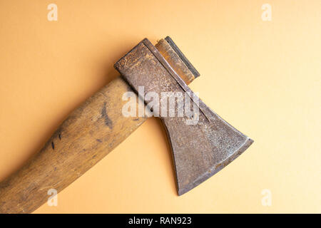 The old ax lies on the ground . Old ax with wooden handle on light brown background. Top view. Stock Photo
