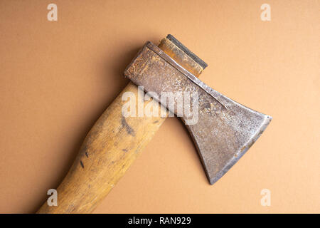 The old ax lies on the ground . Old ax with wooden handle on light brown background. Top view. Stock Photo