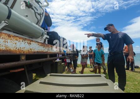 Royal New Zealand Navy Able Diver Hayden Shapcott, assigned to the Royal New Zealand Navy Littoral Warfare Unit, explains the functions of a dive chamber to a group of children during Exercise Fulcrum in Bland Bay, New Zealand, Feb. 17, 2017. Exercise Fulcrum is a combined-joint exercise that integrates U.S. Navy Sailors and Marines from explosive ordnance disposal mobile units with service members from the Royal New Zealand Navy and the Royal Australian Navy. Stock Photo