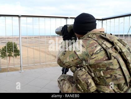 Pvt. Elisha David-Perra, Calvary Scout with the 4th Squadron, 10th Cavalry Regiment (Black Jack), 3rd Armored Brigade Combat Team, 4th Infantry Division, observes for potential enemy reconnaissance forces Mar. 1, 2017. This simulation allows real-time assessments and evaluations throughout the CALFEX. Operation Atlantic Resolve, a U.S. led effort in Eastern Europe that demonstrates U.S. commitment to the collective security of NATO and dedication to enduring peace and stability in the region. Stock Photo