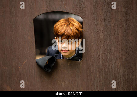 Close up of Red headed boy looking out window outside Stock Photo