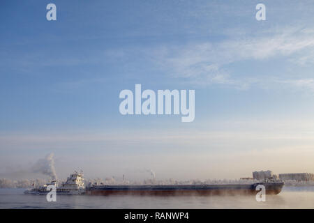 Long barge going down river in cold winter. Stock Photo