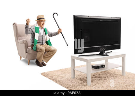 Full length shot of a senior male sports fan with a cane and a scarf sitting in an armchair watching a game on tv and cheering isolated on white backg Stock Photo