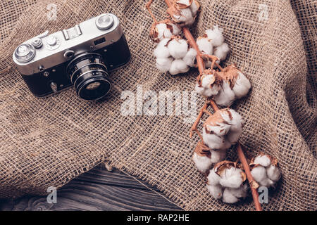Old retro film camera on burlap with a sprig of cotton Stock Photo