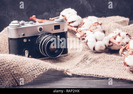 Old retro camera close-up on burlap with cotton on the table Stock Photo