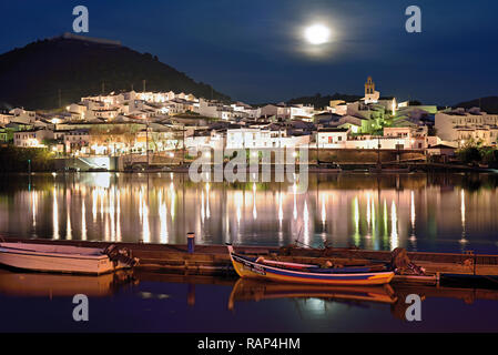 Romantic white washed riverside village with moonlight and wooden fishing boats anchoring at quay (view from Portugal to Spain) Stock Photo