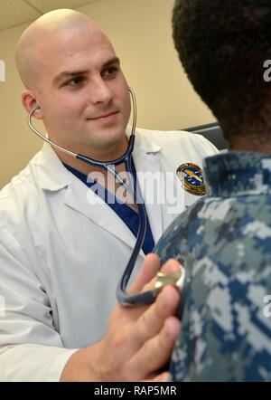 JACKSONVILLE, Fla. (Feb. 2, 2017) – Lt. Aaron Moody, a family medicine physician at Naval Hospital Jacksonville, listens to a patient’s breath sounds. The Navy Medical Corps celebrates its 146th birthday on March 3. Since 1871, Navy physicians have served in multiple specialties while aboard Navy ships at sea, in aviation and undersea medicine, with Marines in field hospitals, and on humanitarian and disaster relief missions. Stock Photo