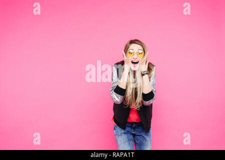 Emotion teen girl in yellow sunglaases against pink studio background. Stock Photo