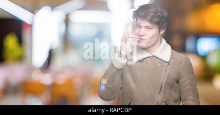 Young handsome man wearing winter coat over isolated background mouth and lips shut as zip with fingers. Secret and silent, taboo talking Stock Photo