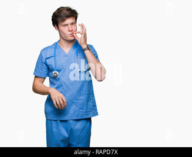 Young doctor wearing medical uniform over isolated background mouth and lips shut as zip with fingers. Secret and silent, taboo talking Stock Photo