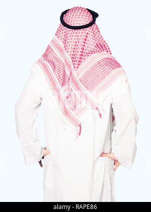Arabian business man with long hair wearing traditional keffiyeh scarf standing backwards looking away with arms on body Stock Photo