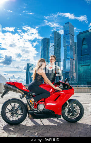 Portrait in full growth, young couple on a sports bike on the background of the city skyline Stock Photo