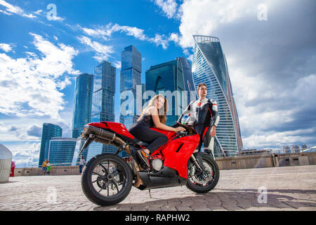 Portrait in full growth, young couple on a sports bike on the background of the city skyline Stock Photo