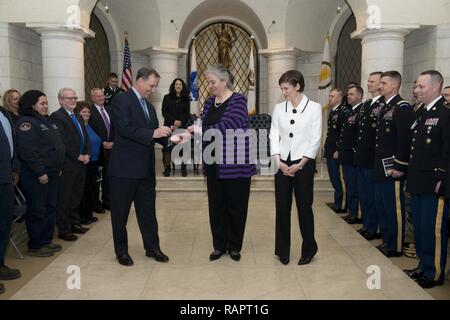 From the left, Gerald B. O’Keefe, administrative assistant to the Secretary of the Army, gives an Senior Executive Service pin to Kathryn Condon, former executive director of Army National Military Cemeteries, to place on Katharine Kelley, superintendent, Arlington National Cemetery, during Kelley’s SES induction ceremony, March 2, 2017, in Arlington, Va. The ceremony took place in the lower level of the Memorial Amphitheater in the cemetery. Stock Photo
