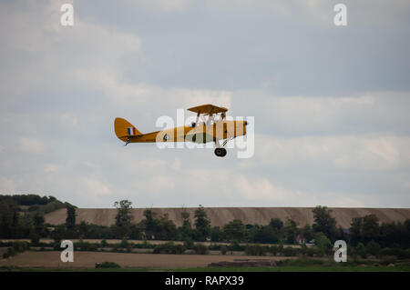 A yellow biplane flies over Duxford Imparial War Museum Stock Photo