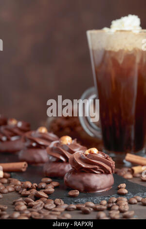 Chocolate dessert with hazelnut and coffee with cream on a wooden table.Coffee beans and cinnamon sticks are scattered on the table. Stock Photo