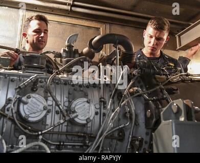 SOUTH CHINA SEA (March 3, 2017) Gas Turbine System Technician 2nd Class Andrew Mesenbrink (left), from Killen, Alabama, teaches Lt. j.g. Michael Murphy, from Indianapolis, Indiana, about gas turbine generators during a tour of an engine room aboard Arleigh Burke-class guided-missile destroyer USS Wayne E. Meyer (DDG 108). Wayne E. Meyer is on a regularly scheduled Western Pacific deployment with the Carl Vinson Carrier Strike Group as part of the U.S. Pacific Fleet-led initiative to extend the command and control functions of U.S. 3rd Fleet into the Indo-Asia-Pacific region. U.S. Navy aircraft Stock Photo