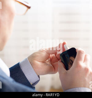 Mid age Man doing blood test with personal glucometer Stock Photo