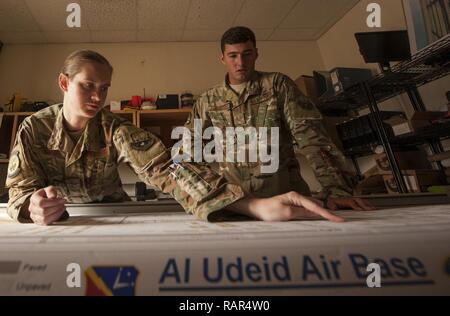 Senior Airman Jessica Kraus, 379th Expeditionary Civil Engineer Squadron geobase technician, and  Staff Sgt. Arich Bosshart, 379th ECES geobase manager NCO in charge, look over an installation map prior to trimming its edges Dec. 11, 2018, at Al Udeid Air Base, Qatar. Bosshart and Kraus are responsible for creating and updating installation maps with the use of geospatial information system equipment and automated computer-aided design and drafting software. They also provide surveying support to construction that occurs on Al Udeid. Stock Photo
