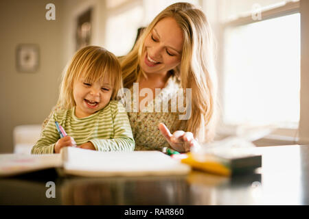 Young girl playing with a coloring book with her mother. Stock Photo