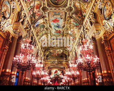 Interior of Opera Garnier Palace and a golden painted ceiling with a lot of chandeliers hangining in Paris, France. Stock Photo